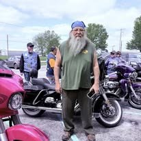 Rider standing among motorcycles at a community event