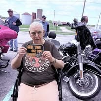 Community member holding an event keepsake beside motorcycles