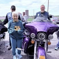 Community participant standing beside a purple motorcycle